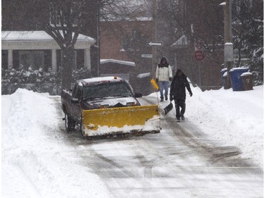 A driveway-clearing crew walks along Curzon St. in the Montreal West area of Montreal Tuesday, December 29, 2015 during the city's first major snow fall of the 2015-2016 winter.