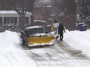 A driveway-clearing crew walks along Curzon St. in the Montreal West area of Montreal Tuesday, December 29, 2015 during the city's first major snow fall of the 2015-2016 winter.