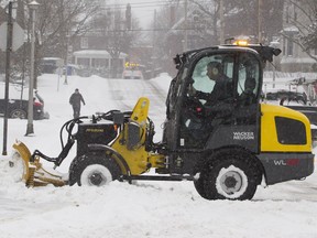 A sidewalk plow clears the intersection of Westminster Ave. N. and Curzon St. in the Montreal West area of Montreal Tuesday, December 29, 2015 during the city's first major snow fall this winter.