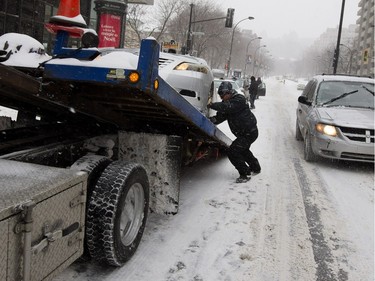 A tow truck driver removes a taxi from Atwater Avenue in Montreal on Tuesday December 29, 2015. Montreal received its first major snow fall after a very warm start to the winter.