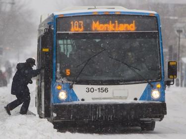 A woman climbs over a snow bank to board a bus in N.D.G. in Dec. 2015.