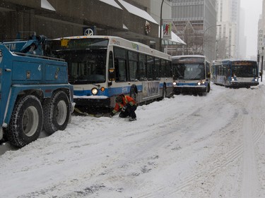 MONTREAL, QUE.: DECEMBER 29, 2015-- An STM tow truck drivers pulls STM buses out of the snow on Robert Bourassa Boulevard in Montreal on Tuesday December 29, 2015. Montreal received its first major snow fall after a very warm start to the winter. (Allen McInnis / MONTREAL GAZETTE)