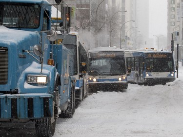 An STM tow truck drivers pulls STM buses out of the snow on Robert Bourassa Boulevard in Montreal on Tuesday December 29, 2015.