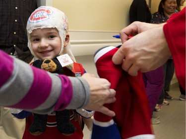 Maxence Gosselin smiles as his mother takes a jersey that Montreal Canadiens Jarred Tinordi  signed for him as the Montreal Canadiens visit the Montreal Children's Hospital in Montreal on Tuesday December 8, 2015.