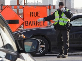 File photo: A police officer directs traffic to Girouard Ave. from St-Jacques St. in Montreal, on Monday, March 23, 2015. A section of St. Jacques, a major thoroughfare to get downtown, will be closed for 2.5 years.