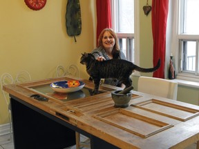 A wooden door is used as a table at Jennifer Cook's home. Cook is seen with her cat, Sparky. (Marie-France Coallier / MONTREAL GAZETTE)