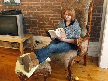 Jennifer Cook reads a book in her living room. She lives in a 1,400-square-foot condo. Cook, a graphic artist, works from home. Her furniture is an eclectic mix of old (inherited from family) and new. (Marie-France Coallier / MONTREAL GAZETTE)