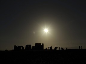 People are silhouetted as the sun rises above the ancient stone circle of Stonehenge, in southern England, as access to the site is given to Druids, New Age followers and members of the public on the annual Winter Solstice, Friday, Dec. 21, 2012.