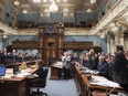 Quebec Premier Philippe Couillard, right, is applauded by members of the legislature after he gave his holiday greetings as the fall session comes to an end, Friday, Dec. 4, 2015 at the legislature in Quebec City.