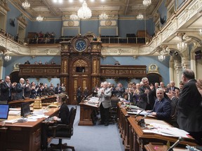 Quebec Premier Philippe Couillard, right, is applauded by members of the legislature after he gave his holiday greetings as the fall session comes to an end, Friday, Dec. 4, 2015 at the legislature in Quebec City.