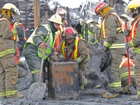 Police and firefighters push a metal case found in the scorched rubble of the Résidence du Havre seniors' home in L'isle-Verte, on Jan. 28, 2014, looking for human remains and other clues.