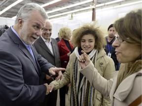 Quebec Premier Philippe Couillard greets newly arrived Syrian refugees at a St-Laurent welcome centre on Saturday, Dec. 13, 2015.