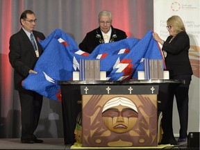 Justice Murray Sinclair (centre) and Commissioners Chief Wilton Littlechild (left) and Marie Wilson pull back a blanket to unveil the Final Report of the Truth and Reconciliation Commission of Canada on the history of Canada's residential school system, in Ottawa on Tuesday, Dec. 15, 2015.