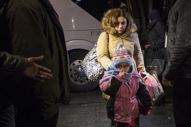 Syrian refugees step off a bus into a hotel after arriving on the first government-arranged flight into Toronto's Pearson Airport, on Friday, Dec. 11, 2015.