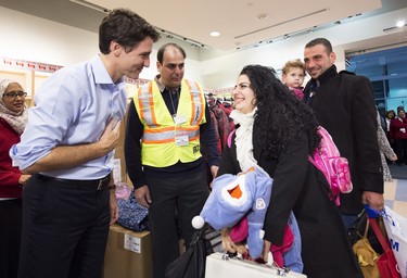 Canadian Prime Minister Justin Trudeau, left, greets new Syrian refugees Georgina Zires, centre, 16 month-old Madeleine Jamkossian, second right, and her father Kevork Jamkossian at Pearson International airport in Toronto.