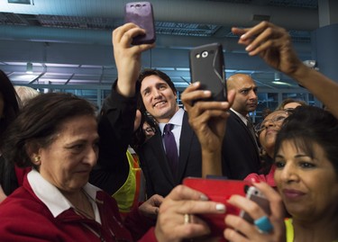 Canadian Prime Minister Justin Trudeau, centre, poses for a selfies with workers before he greets refugees from Syria at Pearson International airport, in Toronto, on Thursday, Dec. 10, 2015.