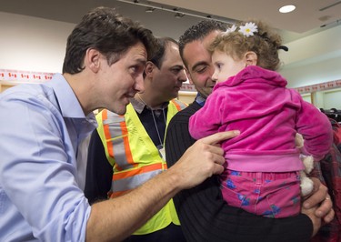 Canadian Prime Minister Justin Trudeau greets 16-month-old Madeleine Jamkossian, right, and her father Kevork Jamkossian, refugees fleeing the Syrian civil war, during their arrival at Pearson International airport, in Toronto, on Friday, Dec. 11, 2015.