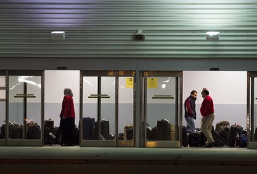 Workers help newly arrived Syrian refugees load their luggage onto busses at Pearson International airport, in Toronto, on Friday, Dec. 11, 2015.