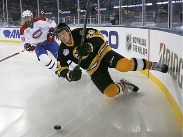 Former Boston Bruins' Tom Fergus, right, falls to the ice in front of former Montreal Canadiens' Eric Desjardins during an alumni outdoor hockey game at Gillette Stadium in Foxborough, Mass., Thursday, Dec. 31, 2015, where the Bruins will play the Canadiens in the NHL Winter Classic on Friday.