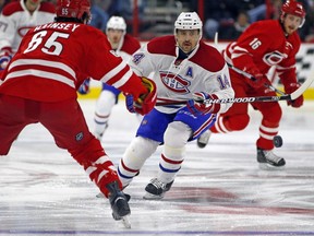 Montreal Canadiens' Tomas Plekanec (14) chips the puck past Carolina Hurricanes' Ron Hainsey (65) during the first period of an NHL hockey game Saturday, Dec. 5, 2015, in Raleigh, N.C.