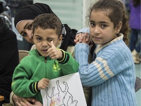 Two Syrian refugee children pose for the camera while their family undergoes the medical screening portion of the Government of Canada's Operation Provision in Beirut, Lebanon Wednesday, Dec. 9, 2015. Crews from CFB Trenton's 427 Squadron are flying the first group of refugees to Toronto, landing there Friday, and the second group to Montreal Saturday.