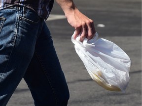 A man carries a plastic bag while leaving a supermarket in Los Angeles, California on September 30, 2014.