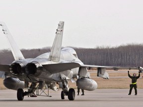 Military personnel guide a CF-18 Hornet into position at the CFB Cold Lake, in Cold Lake, Alberta on Tuesday October 21, 2014.