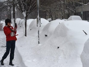 A woman takes pictures of snow covered cars in Washington, D.C,, on Jan. 23, 2016. A deadly blizzard with bone-chilling winds and potentially record-breaking snowfall slammed the eastern U.S. on Saturday, as officials urged millions in the storm's path to seek shelter -- warning the worst is yet to come.