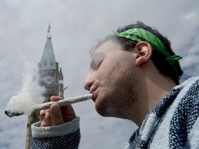 A man smokes a joint at the Fill the Hill marijuana rally on Parliament Hill in Ottawa on Sunday, April 20, 2014.
