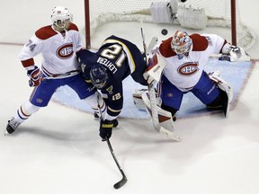 St. Louis Blues' Jori Lehtera is upended as he reaches for a loose puck between Canadiens goalie Mike Condon and Alexei Emelin, left, during the first period of an NHL hockey game Saturday, Jan. 16, 2016, in St. Louis.