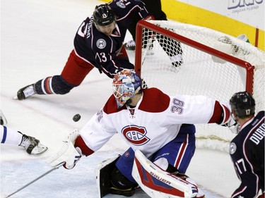 Columbus Blue Jackets' Cam Atkinson, top, shoots the puck behind Montreal Canadiens goalie Mike Condon during the third period of an NHL hockey game in Columbus, Ohio,  Monday, Jan. 25, 2016. Atkinson scored his third goal of the game. The Blue Jackets won 5-2.