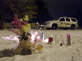 Candles and flowers placed as a memorial lay near the La Loche, Saskatchewan, junior and senior high school as police investigate the scene of a daytime shooting at the school on Saturday, Jan. 23, 2016.