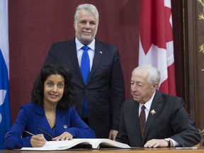 Economy, Science and Innovation Minister Dominique Anglade, left, is sworn in during a ceremony, Thursday, January 28, 2016 at the legislature in Quebec City as Quebec Premier Philippe Couillard, centre and Lt. Governor J.Michel Doyon look on.