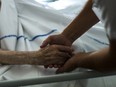 A file picture taken on July 22, 2013 shows a nurse holding the hand of an elderly patient at the palliative care unit of the Argenteuil hospital, outside Paris.