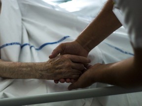 A file picture taken on July 22, 2013 shows a nurse holding the hand of an elderly patient at the palliative care unit of the Argenteuil hospital, outside Paris.