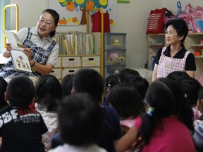 Ikuyo Kotani, 63, left, reads a picture book to kindergarden children with Toshie Kimura, 77, at Kurumi Kindergarden in Kashiwa City, Chiba Prefecture, Japan, on Thursday, June 28, 2012.