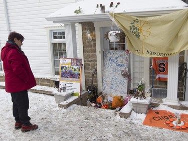 Isabelle Gosselin, a former day-care teacher of Charlelie Carrier, looks at a makeshift memorial outside the Lac-Beauport home Monday, January 18, 2016 near Quebec City where he lived with his parents.
