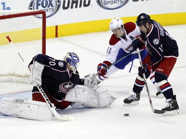 Columbus Blue Jackets goalie Joonas Korpisalo, left, of Finland, stops a shot in front of Montreal Canadiens' Brendan Gallagher, centre, and Blue Jackets' Brandon Dubinsky during the third period of an NHL hockey game in Columbus, Ohio, Monday, Jan. 25, 2016. The Blue Jackets won 5-2.
