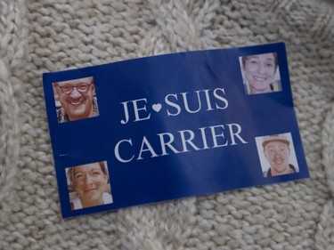 A young woman wears a sticker to honour slain members of the Carrier family at a vigil held in Lac Beauport Monday, January 18, 2016, for them.