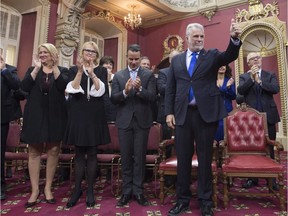 Quebec Premier Philippe Couillard, right, gives the thumbs up as he stands in front of his new cabinet, during a ceremony, Thursday, January 28, 2016 at the legislature in Quebec City. Deputy Premier Lise Theriault, from the left, caucus president Nicole Menard, Whip Stephane Billette and Quebec Finance Minister Carlos Leitao, behind right, stand behind.