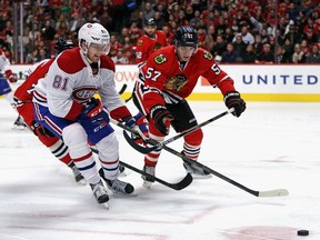 Lars Eller of the Canadiens chases down the puck with Dennis Rasmussen No. 70 and Trevor van Riemsdyk No. 57 of the Chicago Blackhawks at the United Center on Jan. 17, 2016, in Chicago.