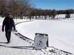 A man walks by the edge of Beaver Lake on Mount Royal, on Friday Jan. 22, 2016, in Montreal. The lake's natural skating rink is off limits due to the ice not being thick enough. The city is waiting for an expert's report on why the ice is not forming properly.