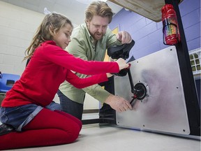 Mario Leroux, president of Bouger Pour Réussir, helps adjust a bicycle desk for seven-year-old Megan Thibault on Tuesday Dec. 15, 2015.