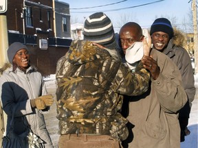 Drummondville resident Laurent Lagueux,  middle, covers Boubacar Sidi Diatta's ear with his scarf during a cold day in Drummondville on Tuesday. Two of four  of the Senegalese father's grown-up children, Kine Diatta, 33, left and Biram Diatta, 35, right, look on laughing.The family just arrived in Drummondville two months ago and were welcomed by RID, the intercultural committee in Drummondville.