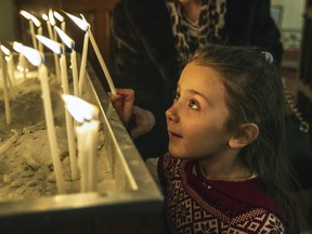 Carni Tokatelian, 6, lights a candle as she arrives with her family for Orthodox Christmas mass at Saint Gregory the Illuminator Armenian Cathedral in Outremont, in Montreal Wednesday January 06, 2016.