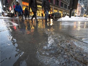 Water from a broken pipe spurts up through cracks along the sidewalk at the corner of rue Se-Catherine and Peel in downtown Montreal Friday, January 1, 2016.