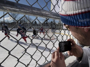 A Montreal Canadiens fan tries to watch the team practice in Parc Emile in Laval on Monday, Jan. 11, 2016. The Canadiens practiced on the new Montreal Canadiens Foundation Blue Blanc Rouge rink in the park after the opening ceremony