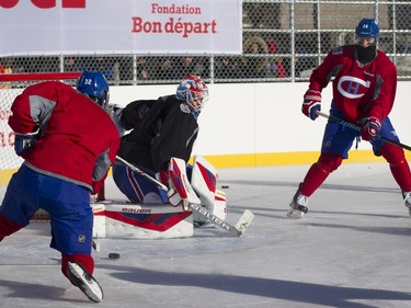 Montreal Canadiens defenseman Nathan Beaulieu, right, passes the puck to right wing Brian Flynn as goalie Mike Condon follows the play during a team practice in Parc Emile in Laval on Monday, Jan. 11, 2016.