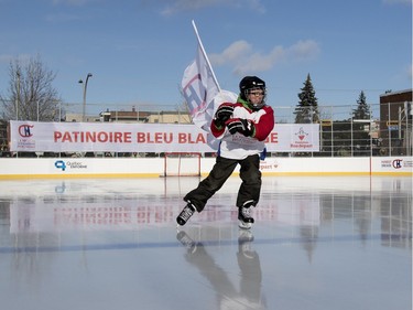 Renault, a young boy from Ecole Leon Guilbault, carries the Montreal Canadiens Foundation flag as he is the first skater to open the new rink in Parc Emile in Laval on Monday, Jan. 11, 2016. The Canadiens practiced on the new Montreal Canadiens Foundation Blue Blanc Rouge rink after the opening ceremony.