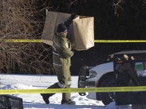 A Sûreté du Québec officer leaves the scene of a police shooting with a bag believed to contain a chainsaw, outside a home in Saint-Joseph-du-Lac, north of Montreal, Jan. 21, 2016. A man allegedly threatened police with the chainsaw.